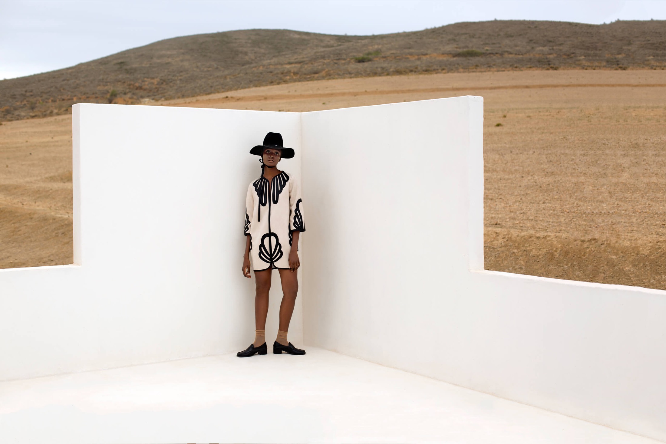 Editorial hair and make-up in black and white, model with wide-brim hat in the desert